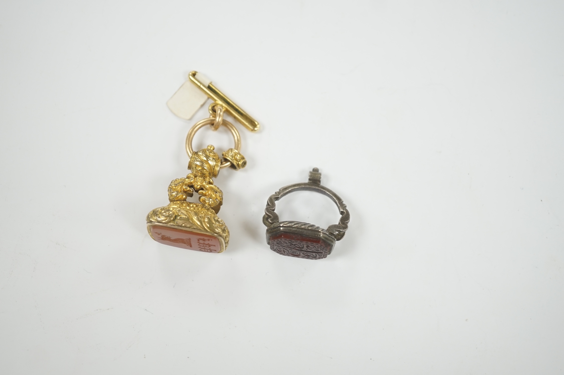 A 19th century gilt metal overlaid and carnelian set fob seal, 36mm, together with a white metal and chalcedony set fob seal, the matrix carved with Persian script.